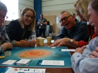 Foto af fem personer, der sidder og spiller Teamleader-spillet